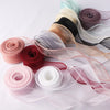 A collection of rolled and unwound wavy edge organza ribbons in various shades of pink, red, black, and white.