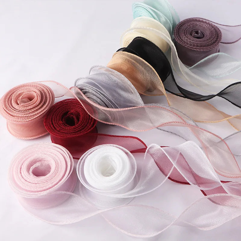 A collection of rolled and unwound wavy edge organza ribbons in various shades of pink, red, black, and white.
