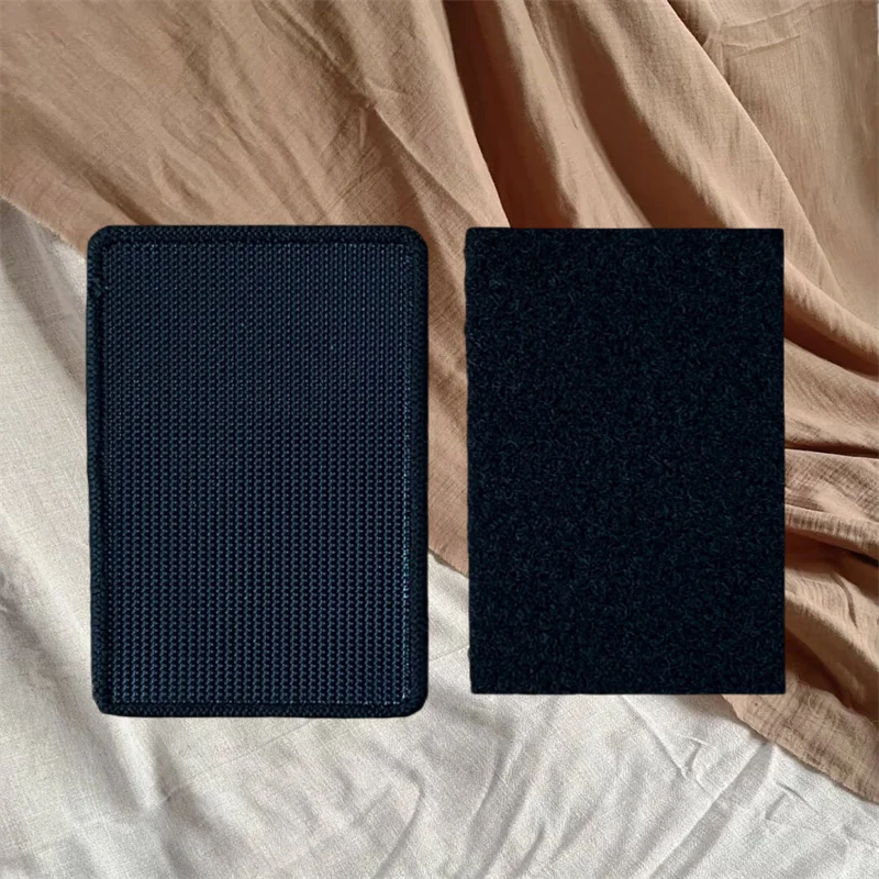 A pair of black hook and loop accessories resting on a beige fabric background.