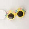 Yellow sunglasses decorated with colorful birthday text on a white background.