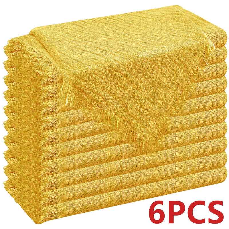 A stack of six golden yellow decorative cloth napkins with fringed edges.