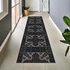 A long runner rug with vintage tribal geometric patterns in shades of gray and navy blue placed on a light tile floor.