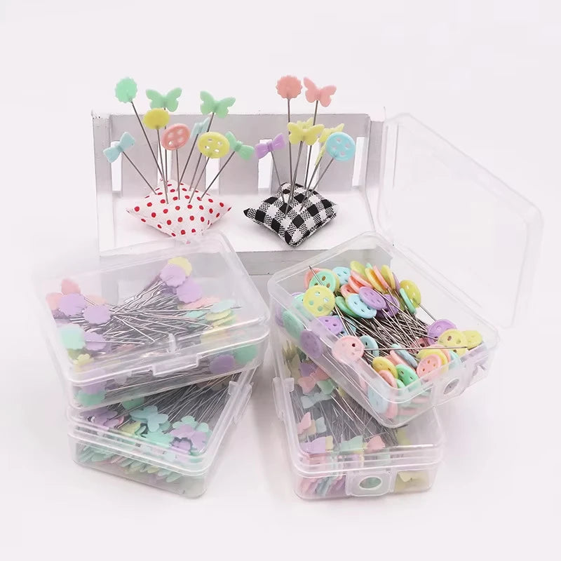 A bulk set of colored sewing pins for crafting displayed in clear plastic containers and a cardboard holder.
