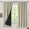 A pair of beige thermal blackout curtain panels hanging on a window.