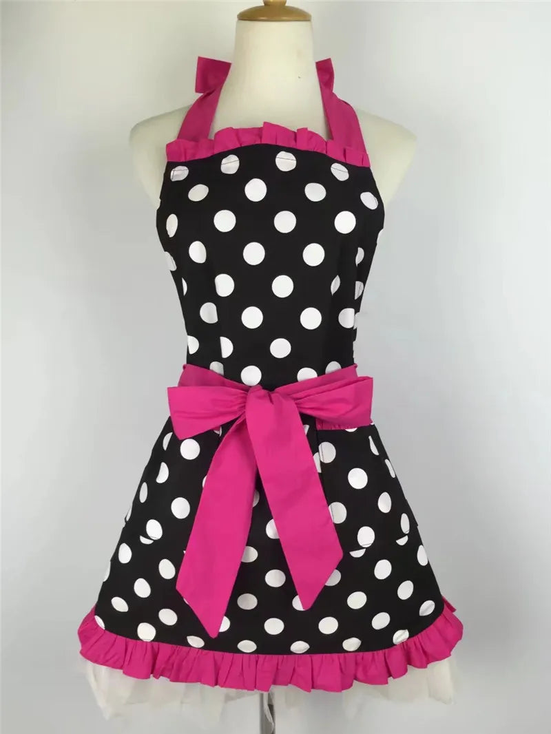 A black polka dot apron with pink ruffled trim and a large pink bow displayed on a mannequin.