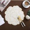 Gold plated peony coasters with delicate floral patterns placed on a dark brown surface.