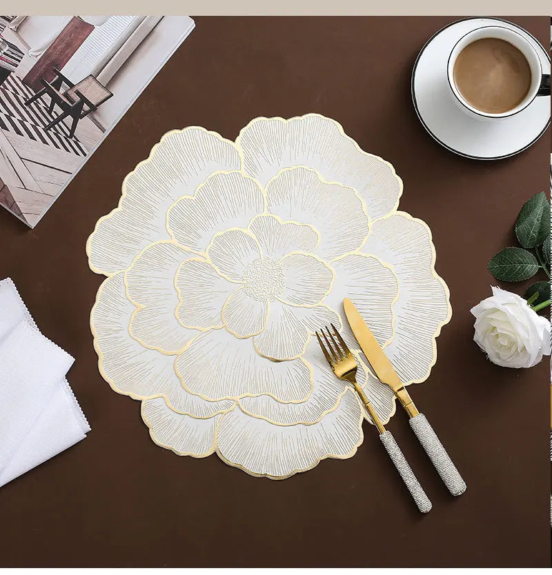 Gold plated peony coasters with delicate floral patterns placed on a dark brown surface.