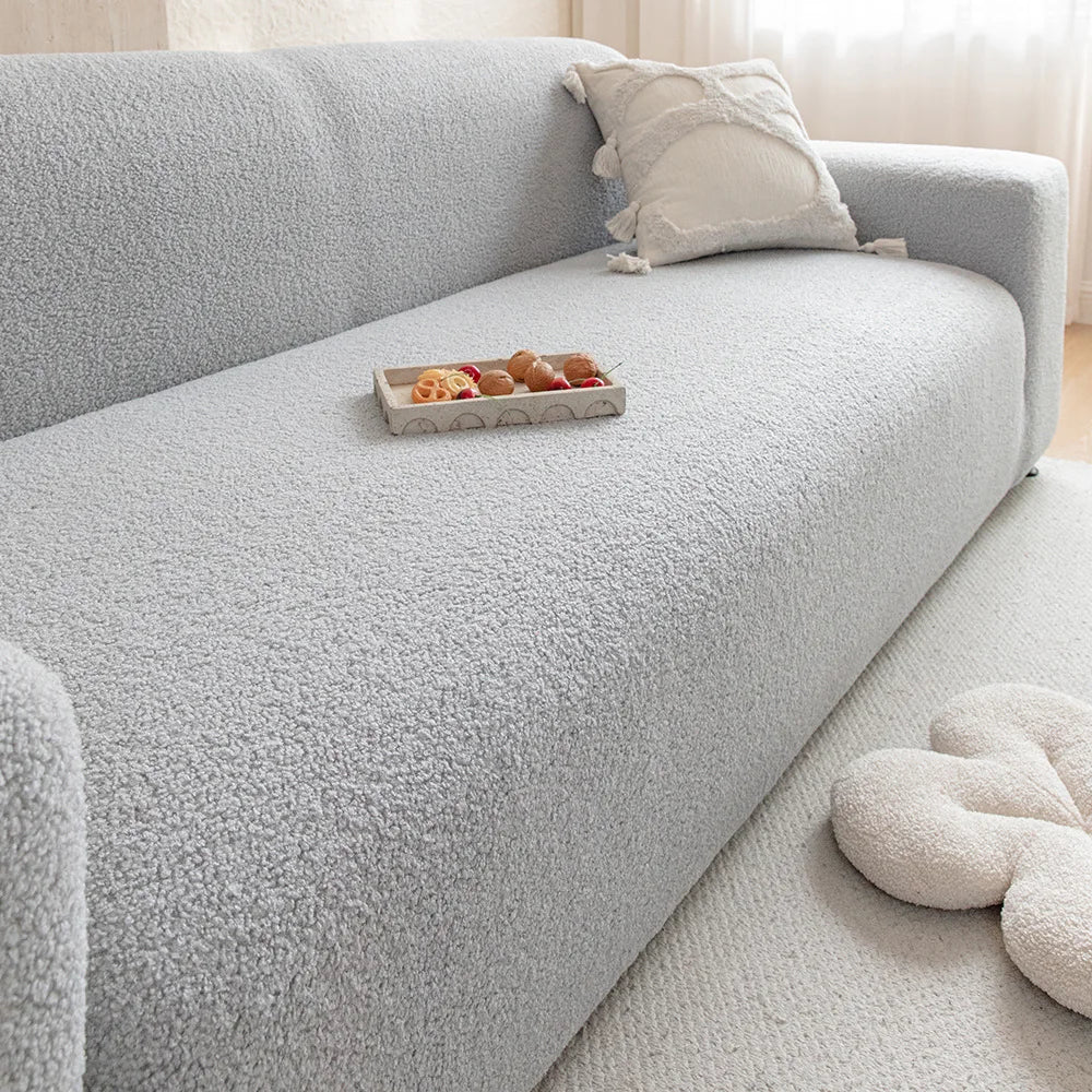 A light gray Jacquard velvet sofa cover with a decorative cushion and snacks on the seat.