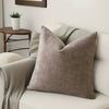 A beige linen textured throw pillow cover resting on a light-colored sofa.