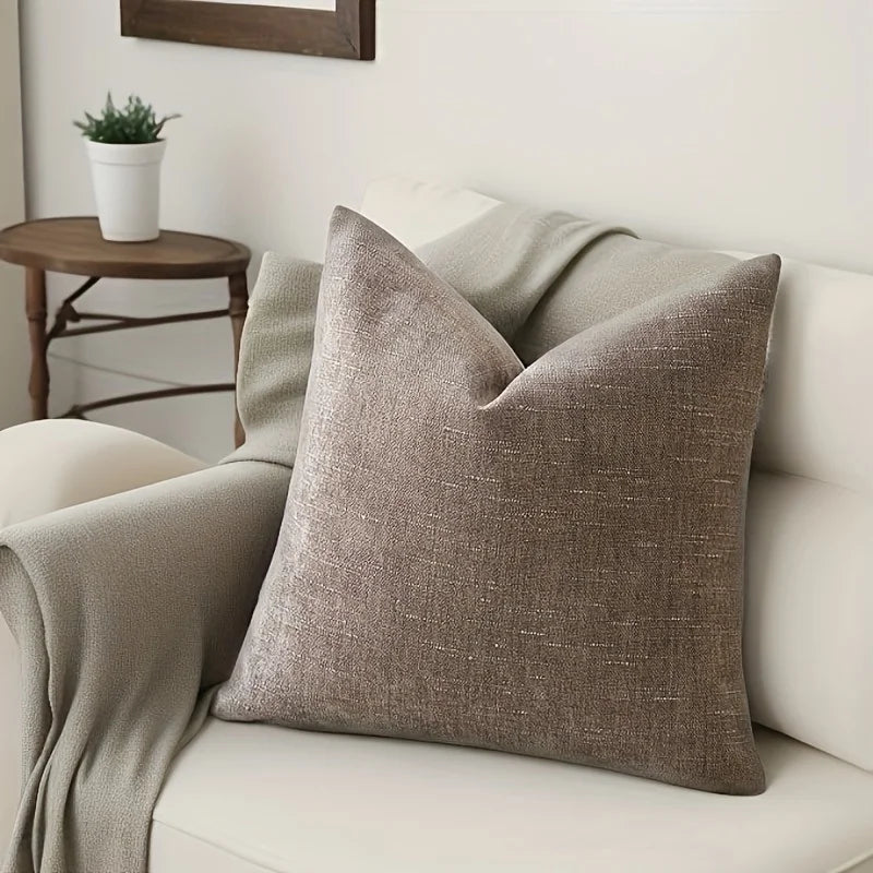 A beige linen textured throw pillow cover resting on a light-colored sofa.