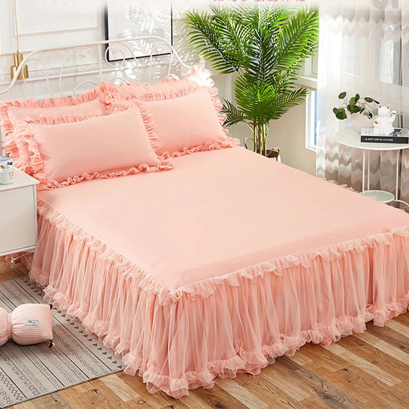 A pink princess lace bed skirt set with ruffled bedding and pillows on a bed.