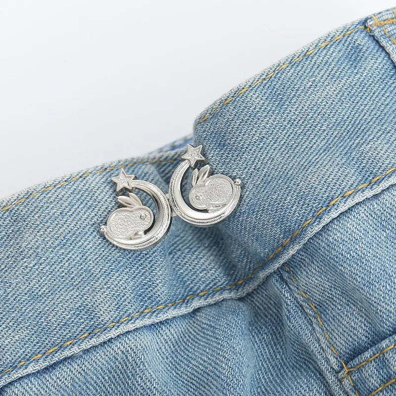 Silver adjustable button clips shaped like leaves are clipped onto a blue denim jean pocket.