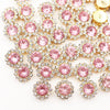 A cluster of pink and clear crystal rhinestone sew-on buttons on a white background.