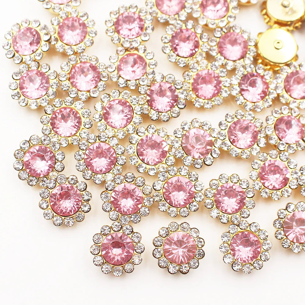 A cluster of pink and clear crystal rhinestone sew-on buttons on a white background.