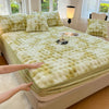 A luxury faux rabbit fur fitted sheet set in pale green and cream colors displayed on a bed.