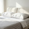 A white hotel-grade memory foam sleeping pillow resting on a white bed with natural light.