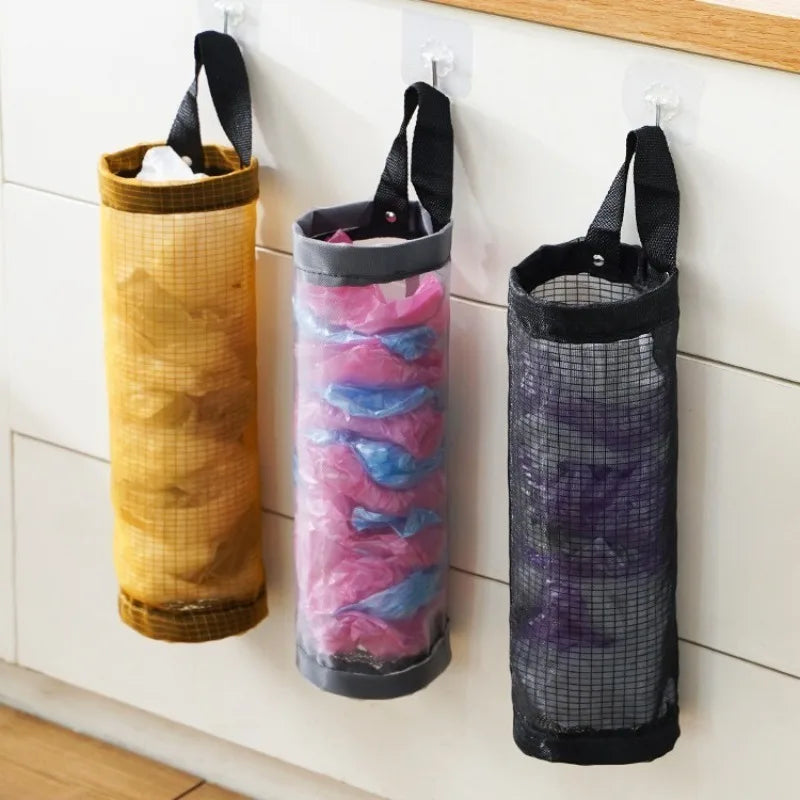 Three hanging mesh trash bags in gold, pink, and purple colors displayed on a white shelf.