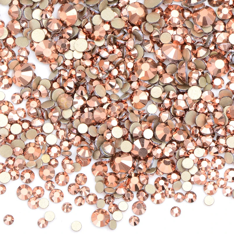 A close-up view of a mix of clear and rose gold glass rhinestones for DIY crafts.