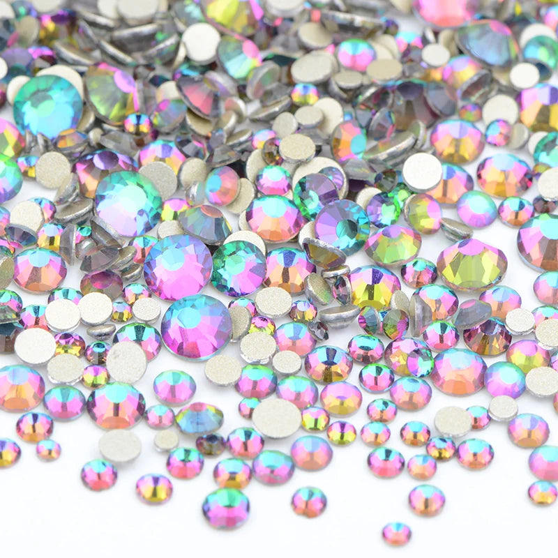 A pile of clear glass rhinestones in various shades of pink, green, and silver for DIY crafts.