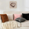 A collection of striped corduroy pillow covers in shades of brown, pink, and gray displayed on a light-colored sofa.