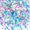 A pile of clear glass rhinestones in various colors including blue, pink, and green for DIY crafts