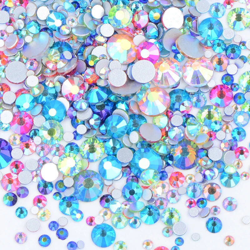 A pile of clear glass rhinestones in various colors including blue, pink, and green for DIY crafts