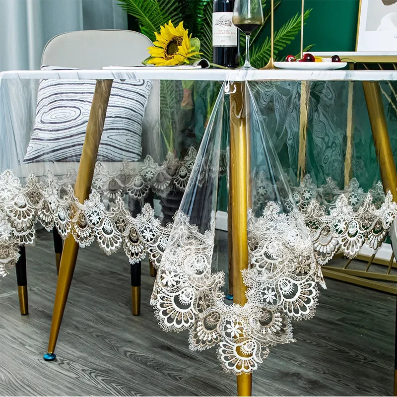 White lace embroidered PVC tablecloth draped over a gold stand on a wooden table.