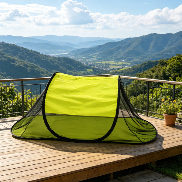 A bright lime green portable pop-up mosquito net shelter spread out on a wooden deck overlooking rolling hills.