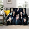 A dark fleece throw blanket featuring a collage of seven male Kpop idols in various poses.