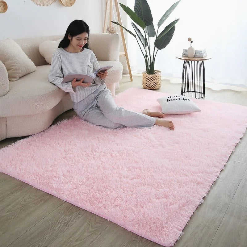A pink fluffy rug is placed on a light wood floor in a living room setting.