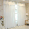 White double-layer blackout curtains with sheer overlay hanging in a light-colored room.