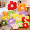 A collection of colorful plush sunflower flowers in red, orange, yellow, and purple arranged on a wooden floor.