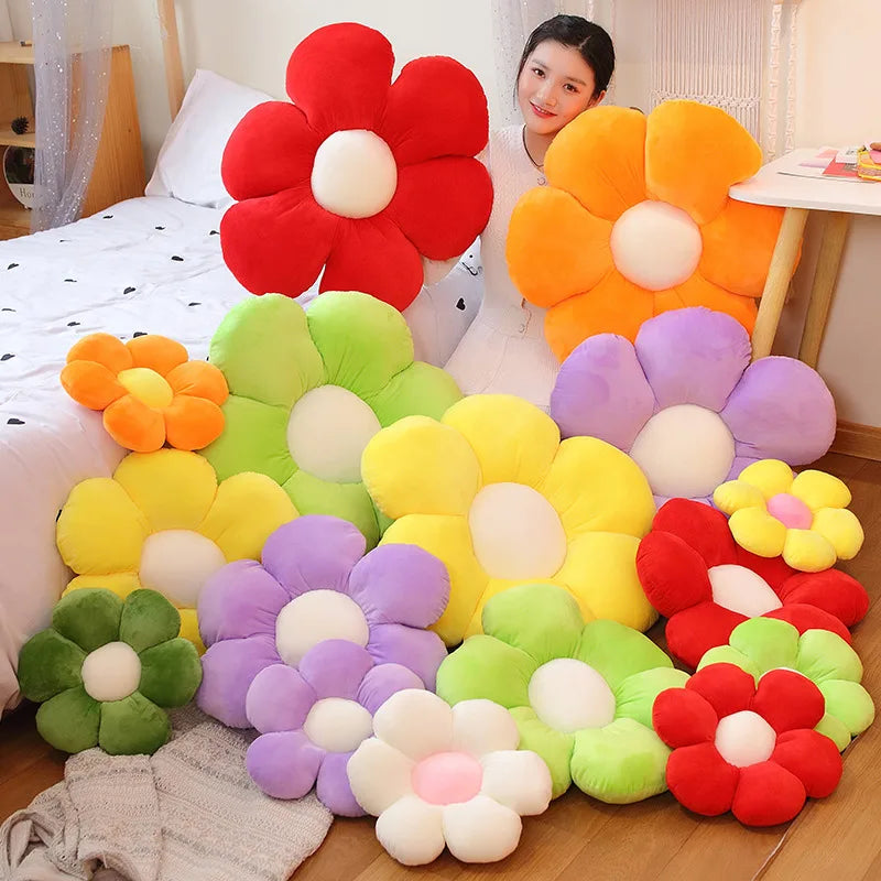 A collection of colorful plush sunflower flowers in red, orange, yellow, and purple arranged on a wooden floor.