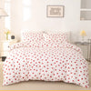 White duvet cover and pillow cases with a red heart print on a bed.