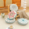 A collection of round, patterned cushions and a woven textile displayed on a light rug next to wooden furniture.