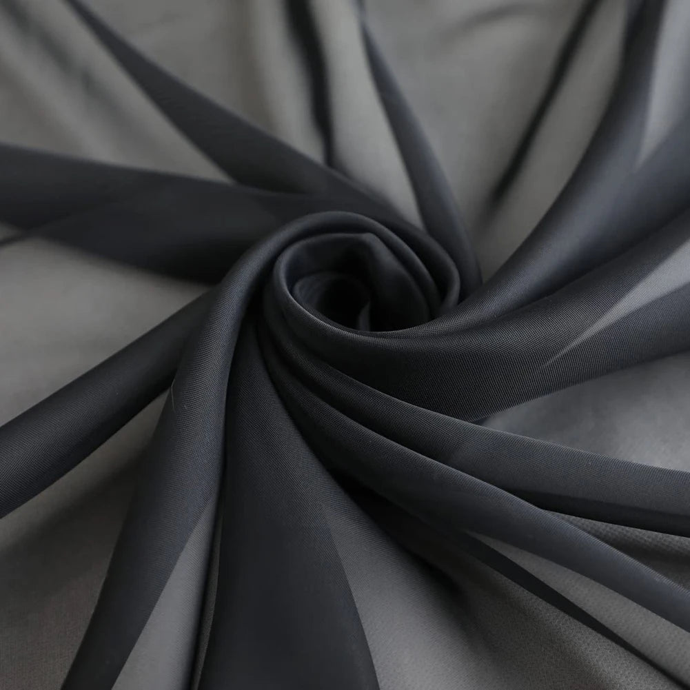 A dark gray sheer voile curtain panel is gathered and draped, showing soft folds and light filtering fabric.