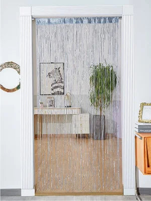 Decorative door string curtains covering a window with sheer white strands and a light wood floor.
