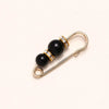 Gold-toned adjustable pearl brooch featuring two black beads accented with small clear stones