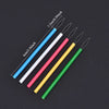 Five colorful needle threaders in blue, white, pink, yellow, and green are displayed against a dark background.