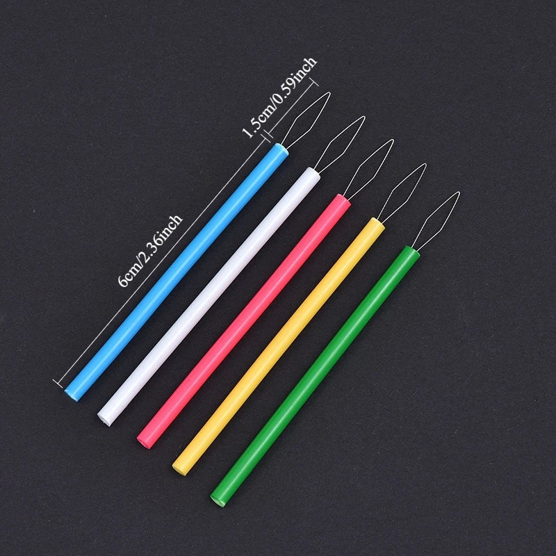 Five colorful needle threaders in blue, white, pink, yellow, and green are displayed against a dark background.
