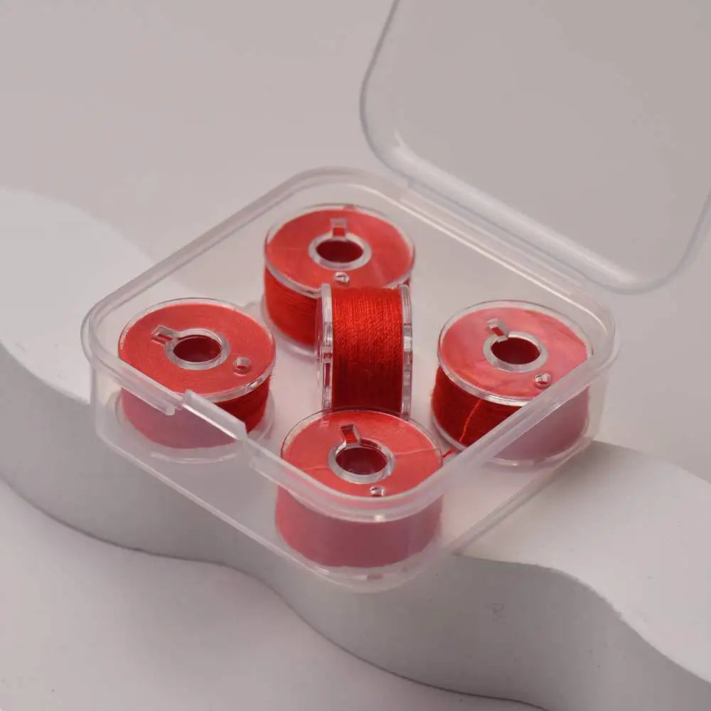 A clear plastic container holds several spools of prewound sewing machine bobbin threads.