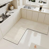 A rectangular beige anti-slip floor mat placed on a white kitchen floor next to a sink and cabinets.