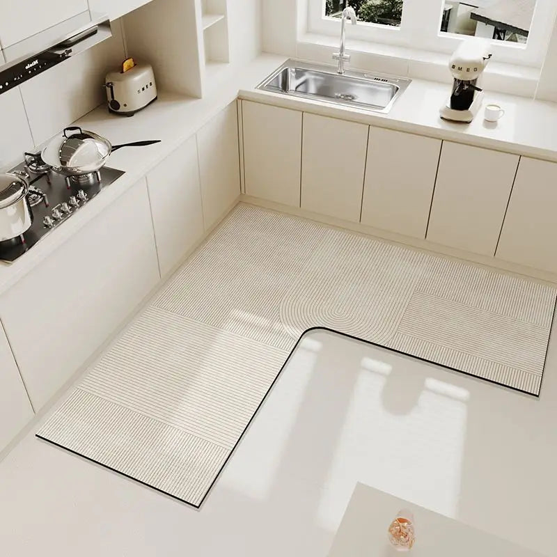 A rectangular beige anti-slip floor mat placed on a white kitchen floor next to a sink and cabinets.