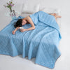 A woman is relaxing on a light blue quilted blanket indoors.