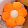 An orange sunflower plush flower cushion with a white center resting on a beige fabric.