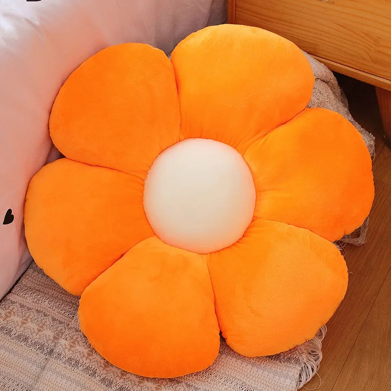An orange sunflower plush flower cushion with a white center resting on a beige fabric.
