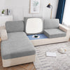 A light gray waterproof jacquard stretch sofa cover displayed on a modern sofa in a bright living room.