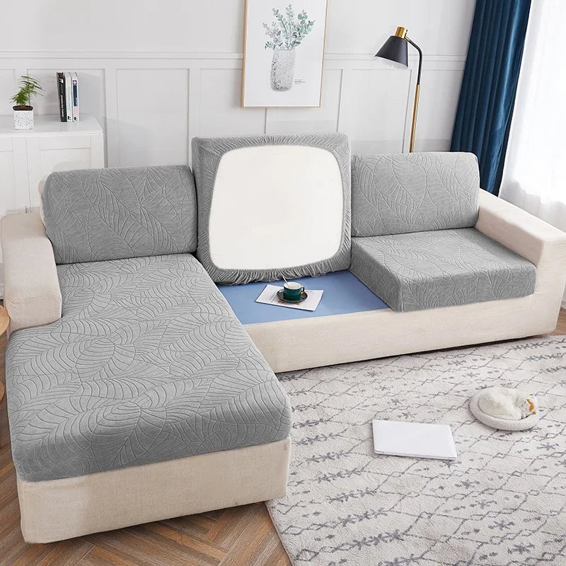 A light gray waterproof jacquard stretch sofa cover displayed on a modern sofa in a bright living room.