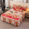 A luxury floral bed skirt with a vibrant pink and red pattern covers a mattress, displayed in a bedroom setting.