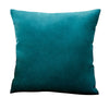 A deep teal velvet throw pillow cover resting on a white background.